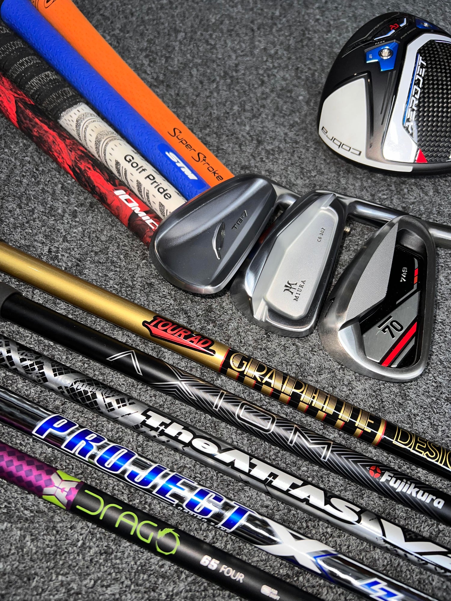 A collection of golf clubs, shafts, and grips.